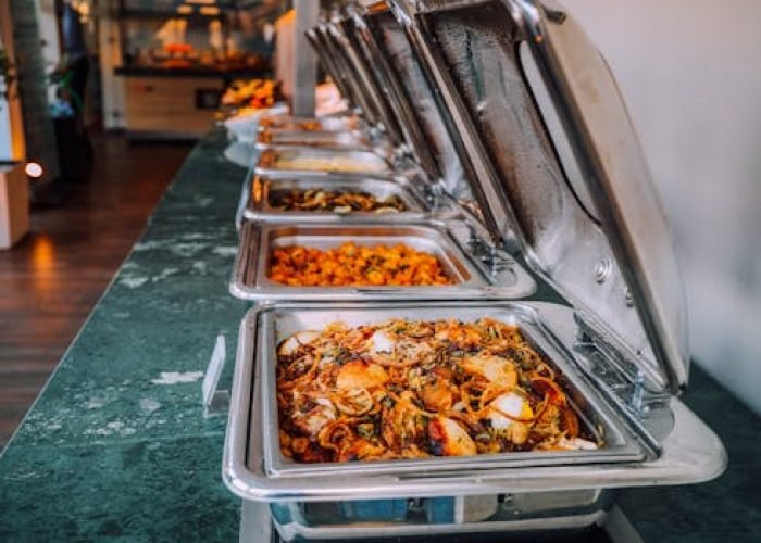 An elegant buffet setup featuring various delicious dishes in stainless steel chafing dishes, perfect for events.